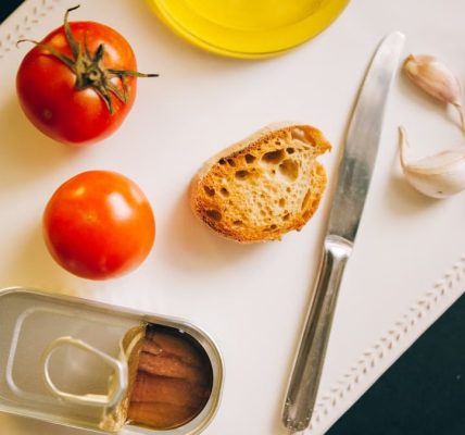 Tomatoes, bread, and sardines arranged for Catalán toast preparation.